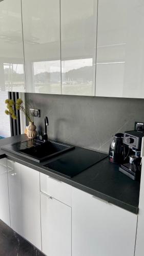 a kitchen with white cabinets and a black counter top at Narusa Leśna Przystań in Frombork
