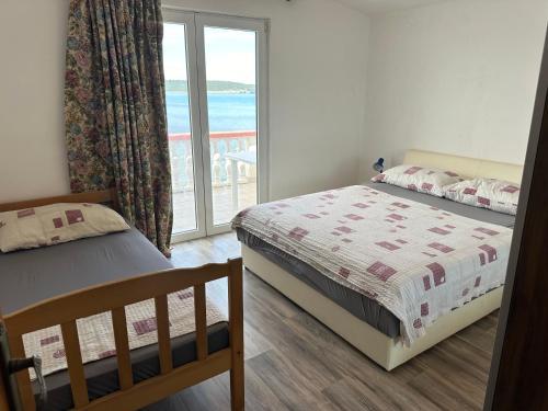 a bedroom with two beds and a view of the ocean at Apartment 2 (+1) in Ljubač