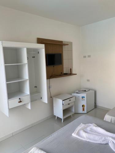 a white room with a bed and a tv at Pousada Good Vibes in Japaratinga