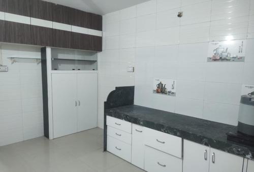a kitchen with white cabinets and a black counter at Shivalaya Homestay in Nashik