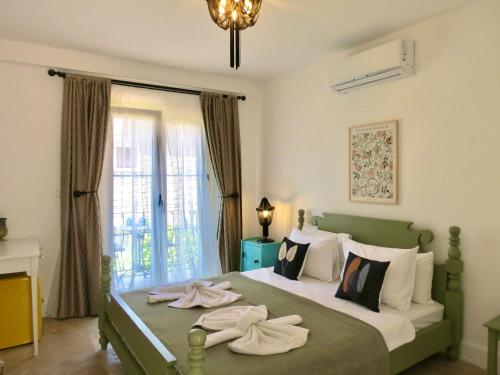 a bedroom with a green bed with towels on it at Fedora Otel Alaçatı in Alaçatı