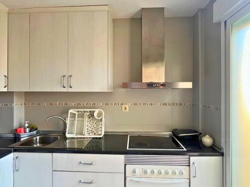 a kitchen with a sink and a stove and cabinets at Home4u Calle Barcelona in Armilla