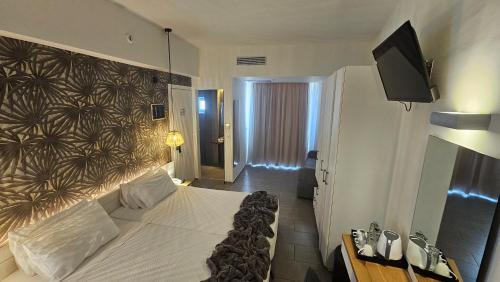 a bedroom with a large bed and a flat screen tv at Atlantis Boutique City Hotel in Rhodes Town