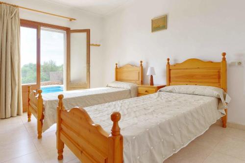a bedroom with two beds and a large window at Villa La Pinta in Santanyi