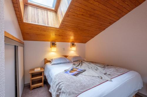 een slaapkamer met een groot bed met een houten plafond bij Résidence Pierre & Vacances Les Sentiers du Tueda in Méribel