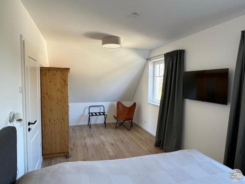 a bedroom with a bed and a window and a chair at Ferienhaus Hornhecht in Born