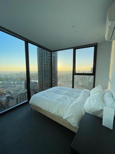 a bedroom with a bed and large windows at C&S Stay- Melbourne CBD in Melbourne