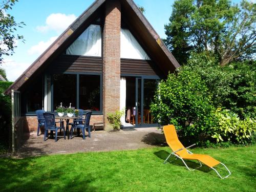 a house with a table and chairs in the grass at Bungalowpark West Friesland in Opmeer