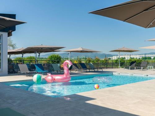 a swimming pool with a pink flamingo in the water at Ibis Styles Colmar Nord in Colmar