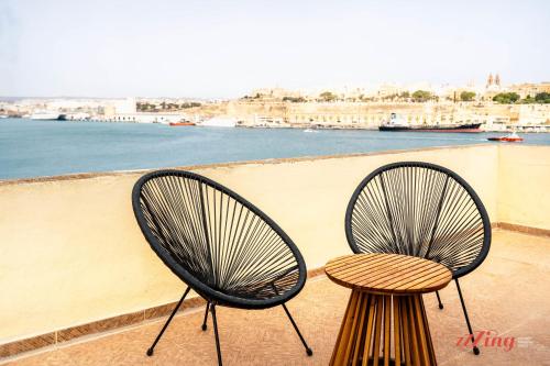 two chairs and a table on a balcony with the water at Charming Historic Home with Rooftop Views in Senglea