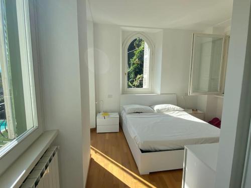 a white bedroom with a bed and two windows at Lake pool&garden house in Meina
