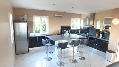 une cuisine avec des placards noirs et un îlot avec des tabourets de bar dans l'établissement Villa Confina, à Villanova