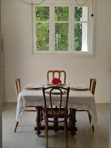 une salle à manger avec une table et des chaises et deux fenêtres dans l'établissement Vacation Rental, à Ambleville
