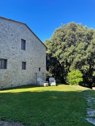 a stone building with two chairs in a yard at La Casina di Borgo Mommialla in Gambassi Terme