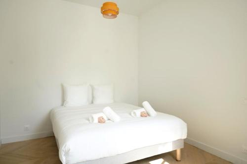 - un lit blanc avec deux poupées au-dessus dans l'établissement Centre les sables - jet d'eau - T2 Paracou, à Les Sables-dʼOlonne