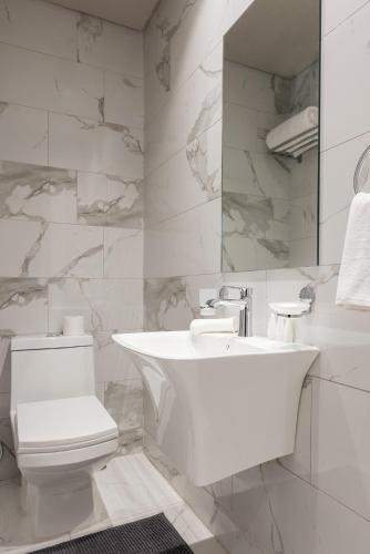 a white bathroom with a sink and a toilet at The Code Residence - ذا كود ريزيدنس in Kuwait