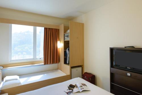 Habitación de hotel con cama y TV en ibis Salvador Rio Vermelho en Salvador