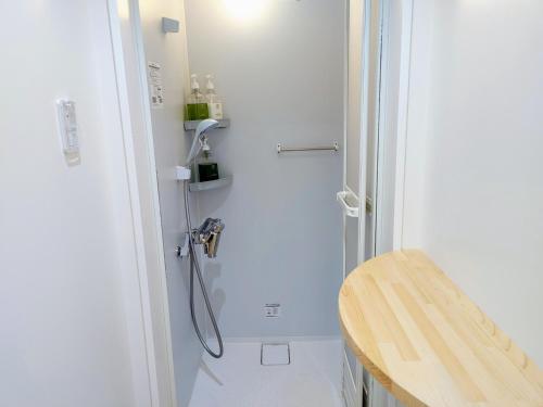 a shower in a white bathroom with a wooden stool at 奏の森リゾート　フォレストグランピング in Ito