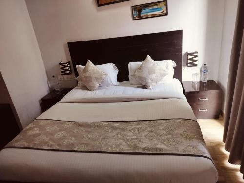 a bedroom with a large bed with white sheets and pillows at Pearl suites at Omaxe entrenity in Vrindāvan