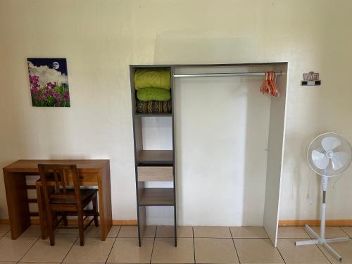 a room with a closet and a desk and a fan at Zoiseaux Paradis in Ravine des Cabris