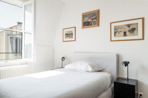 une chambre blanche avec un lit et une fenêtre dans l'établissement Veeve - Literary Radiance, à Paris