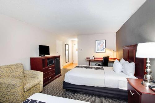 a hotel room with a bed and a chair at La Quinta by Wyndham Indianapolis South in Indianapolis