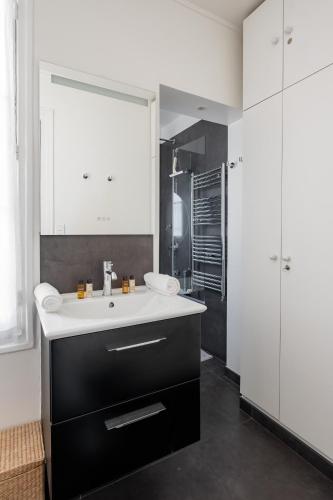 une salle de bain avec un lavabo et un grand miroir dans l'établissement Veeve - Literary Radiance, à Paris