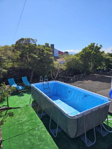 a large blue tub on the grass with two chairs at Casa da estrela canopus in Cabeço Chão