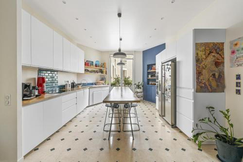 une grande cuisine avec des armoires blanches et une table dans l'établissement Veeve - Gardenside Glamour, à Paris