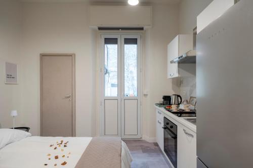 a white room with a bed and a kitchen at Loreto Prestige - Parking Free & Bulb Gym in Milan