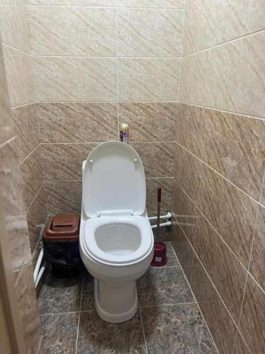 a bathroom with a white toilet in a tiled wall at Milikbek Dodikhudo in Khorog