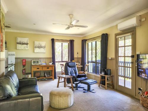 a living room with a couch and chairs and windows at Tarilta Cottage in Hepburn Springs