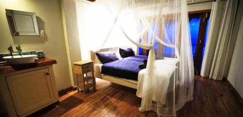 a bedroom with a bed and a sink and a window at Casa Bitonga at Praia da Rocha in Inhambane
