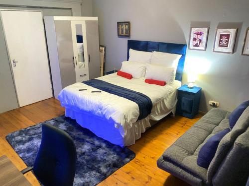 een slaapkamer met een bed, een stoel en een bank bij Rose-Lee Cottage in Durban