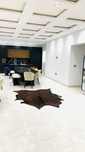 a room with a table and chairs and a rug on the floor at Holy City Gem Modern 4 Bedroom Apartment in Kairwan or Al Qayrawān in Kairouan