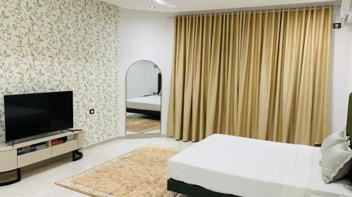 a bedroom with a bed and a tv and a mirror at Holy City Gem Modern 4 Bedroom Apartment in Kairwan or Al Qayrawān in Kairouan