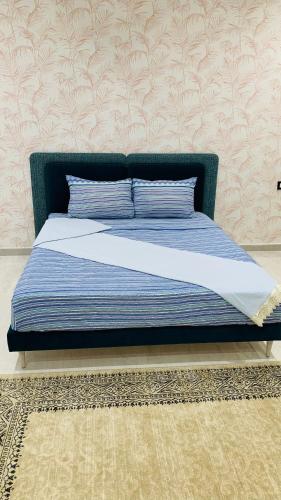 a bed in a bedroom with a blue head board at Holy City Gem Modern 4 Bedroom Apartment in Kairwan or Al Qayrawān in Kairouan
