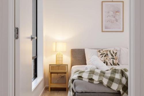 a bedroom with a bed and a table with a lamp at Brand new 4BR Family-friendly house WIFI Garage in Jimboomba