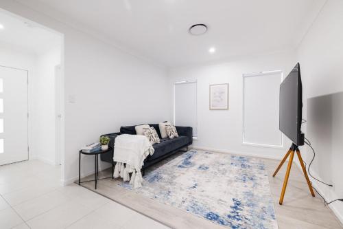 a living room with a black couch and a flat screen tv at Brand new 4BR Family-friendly house WIFI Garage in Jimboomba