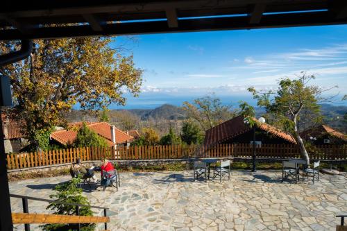 two people sitting in chairs on a patio with a fence at EVIA FOREST VILLAGE in Pappádhes