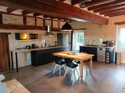 une cuisine avec une table et des chaises en bois dans l'établissement Gîte tout confort avec grand jardin, cheminée, clim et WIFI, proche châteaux de la Loire et ZooParc de Beauval - FR-1-491-400, à Le Controis En Sologne