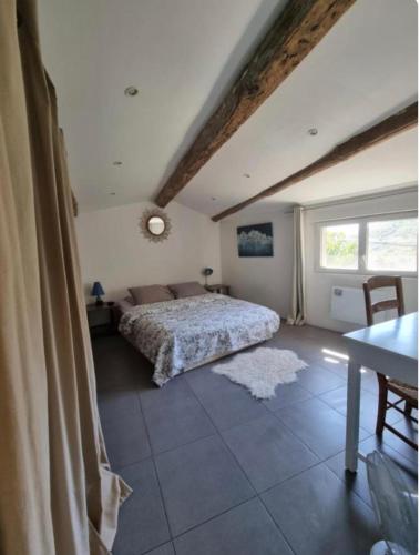 a bedroom with a bed and a table and a window at Mas Montet Chez Raphael in La Valette