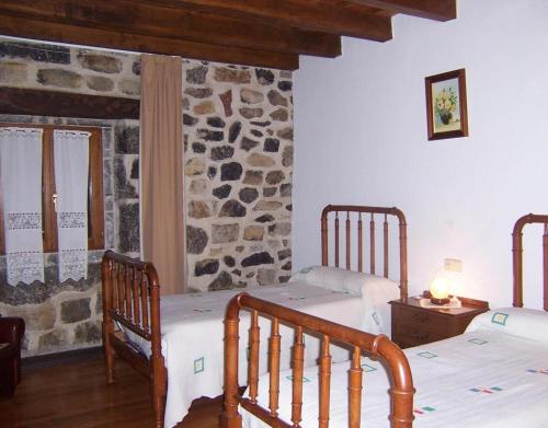 a bedroom with two beds and a stone wall at Casa Rural Barbonea in Lekunberri