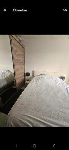 une chambre avec un grand lit avec une tête de lit en bois dans l'établissement Bel appartement proche CDG-PARIS-ASTERIX, à Marly-la-Ville
