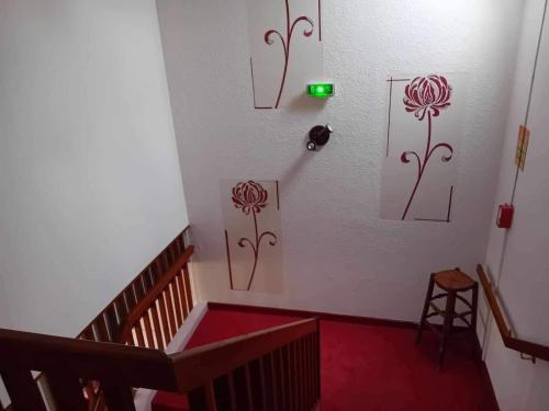 un escalier avec des dessins de fleurs sur le mur dans l'établissement auberge andaine, à La Ferté-Macé