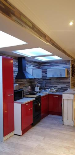- une cuisine avec des placards rouges et une cuisinière noire dans l'établissement Loft centre ville Dijon, à Dijon