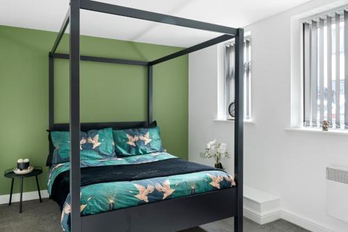a bedroom with a black canopy bed in a room with green walls at Luxury 2 Bed Apartment in Nottingham City Centre in Nottingham