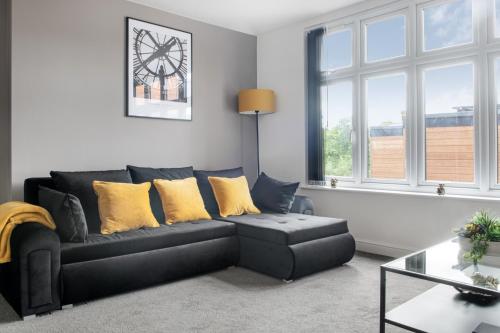 a living room with a black couch and yellow pillows at Luxury 2 Bed Apartment in Nottingham City Centre in Nottingham