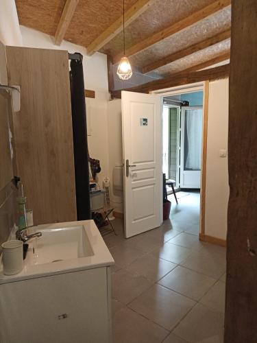 - une cuisine avec un évier et une porte menant à une chambre dans l'établissement La Cordonnerie de Las Places, à Campagne-dʼArmagnac