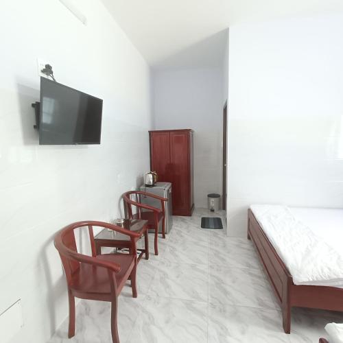 a room with chairs and a bed and a tv at KHÁCH SẠN VĂN KHANG in Bạc Liêu